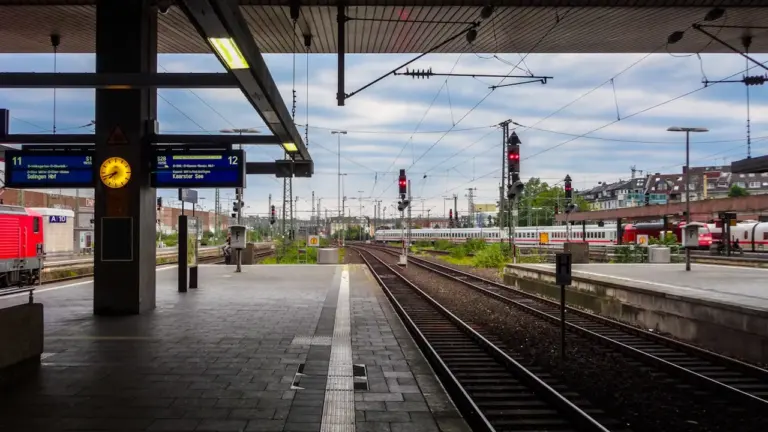 Blick auf einen deutschen Bahnsteig mit Gleisen und digitalen Fahrgastinformationsanzeigen.
