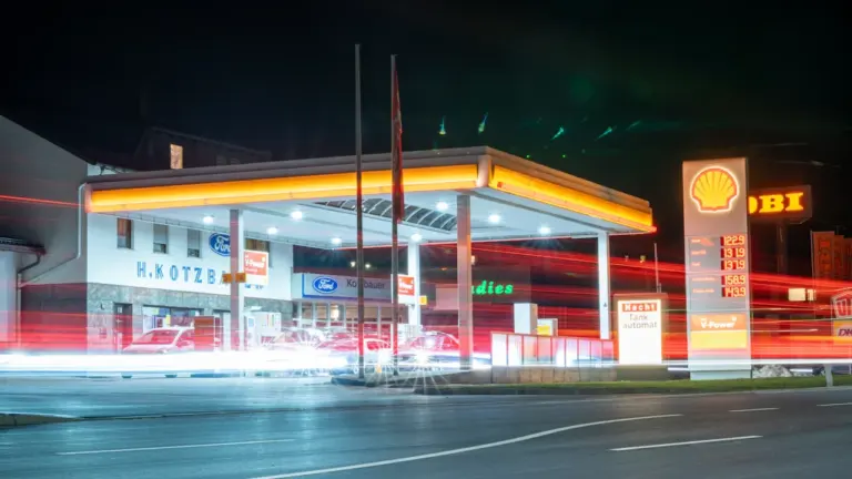 Eine deutsche Tankstelle bei Nacht mit gut sichtbaren Kraftstoffpreisen auf der Preistafel