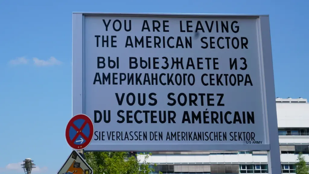 Das berühmte Schild am Checkpoint Charlie in Berlin unter blauem Himmel.