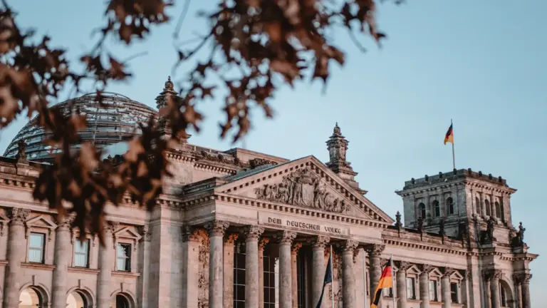 Die deutsche Flagge weht stolz vor dem Reichstagsgebäude in Berlin bei strahlendem Sonnenschein.