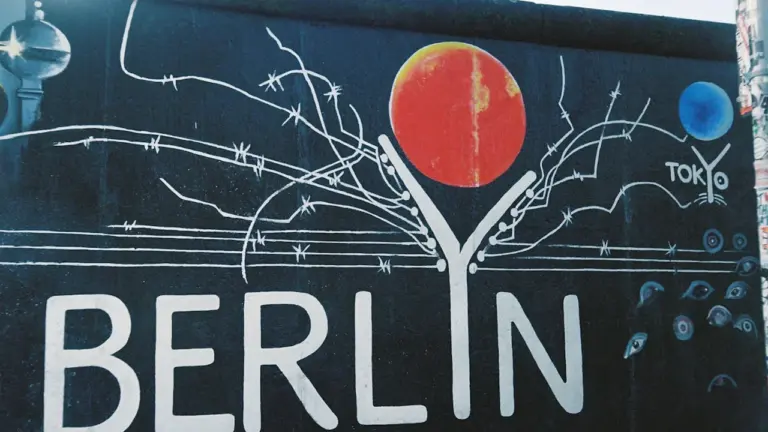 Schwarz-Weiß-Aufnahme eines Graffiti-Kunstwerks auf einem Berliner Mauerfragment mit abstraktem Motiv.