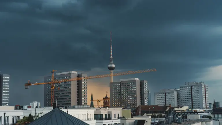 Düstere Gewitterwolken über dem Berliner Fernsehturm und einer städtischen Baustelle.