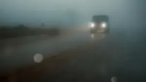 Ein Auto fährt bei starkem Nebel auf einer nassen Landstraße.
