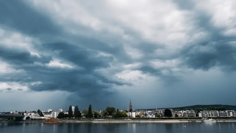 Dramatische dunkle Gewitterwolken über einer deutschen Stadt vor einem einsetzenden Regenschauer.