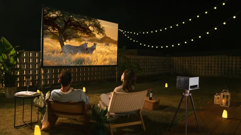 Paar genießt abends einen Film bei sommerlicher Open-Air-Kino-Atmosphäre im Garten.