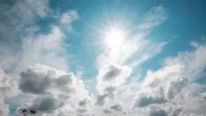 Strahlend blauer Sommerhimmel mit leuchtender Sonne und weißen Wolken am Tag.