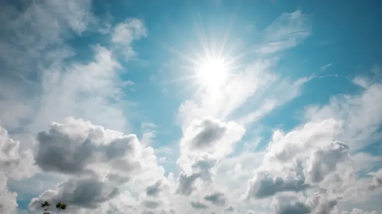 Strahlend blauer Sommerhimmel mit leuchtender Sonne und weißen Wolken am Tag.