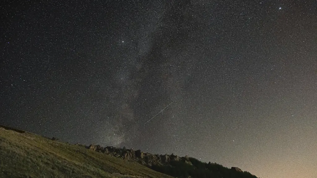 Sternenhimmel über einem sanften Grashügel in der dunklen Nacht.