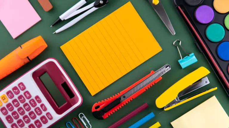 Bunte Schulmaterialien wie Taschenrechner, Stifte und Schere auf einem Schreibtisch.