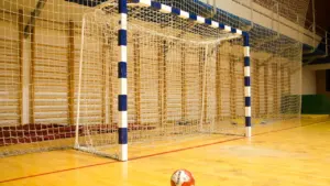 Ein Handballtor mit Ball in einer leeren, hellen Sporthalle für sportliche Wettkämpfe.