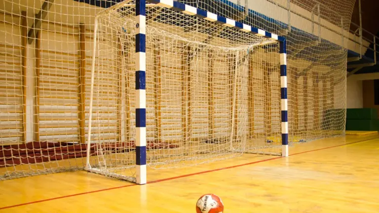 Ein Handballtor mit Ball in einer leeren, hellen Sporthalle für sportliche Wettkämpfe.