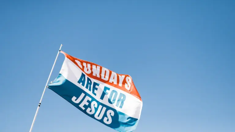 Eine wehende Flagge mit der Aufschrift Sundays Are For Jesus vor blauem Himmel.