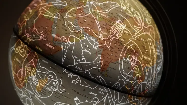 Ein detaillierter Globus mit Sternbildern und astrologischen Symbolen in dunkler Beleuchtung.