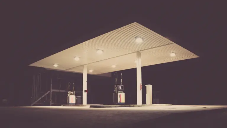 Eine beleuchtete Tankstelle bei Nacht mit Preisanzeige in einer deutschen Stadt.