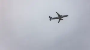 Ein Verkehrsflugzeug zieht seine Bahn durch einen trüben, bedeckten grauen Himmel.
