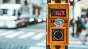 Gelber Fußgänger-Ampelknopf mit einem Aufkleber zum Zurücksetzen der Welt im Stadtbild.