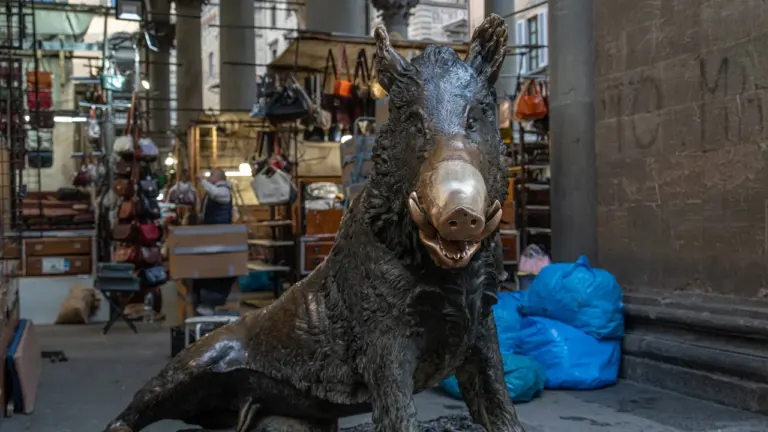 Bronzestatue eines Wildschweins auf einem öffentlichen Platz in städtischer Umgebung bei Tageslicht.