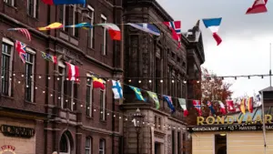 Historisches Gebäude dekoriert mit zahlreichen internationalen Flaggen an einer Lichterkette im Freien.