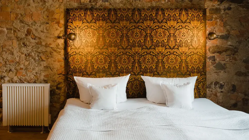 Ein gemütliches Schlafzimmer mit einem Heizkörper vor einer rustikalen Ziegelsteinwand und Doppelbett.