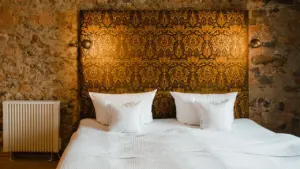 Ein gemütliches Schlafzimmer mit einem Heizkörper vor einer rustikalen Ziegelsteinwand und Doppelbett.
