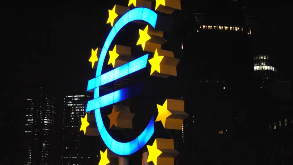 Das leuchtende Euro-Symbol bei Nacht vor einem dunklen Gebäude in Deutschland.