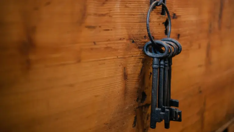 Ein alter, schwarzer Skelettschlüssel hängt an einem massiven Holzhintergrund in Deutschland.