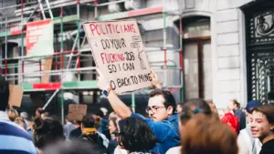 Demonstranten halten ein Protestschild mit der Forderung nach politischem Handeln in einer Stadt.