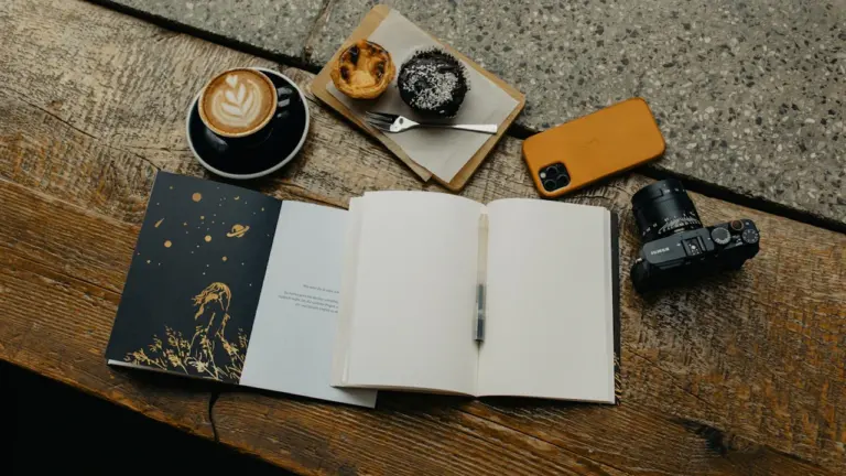 Offenes Notizbuch auf einem Holztisch neben einer Tasse Kaffee für entspannte Planung.