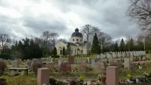 Ein friedlicher sächsischer Friedhof mit einer Kuppelkirche unter einem wolkigen Himmel.