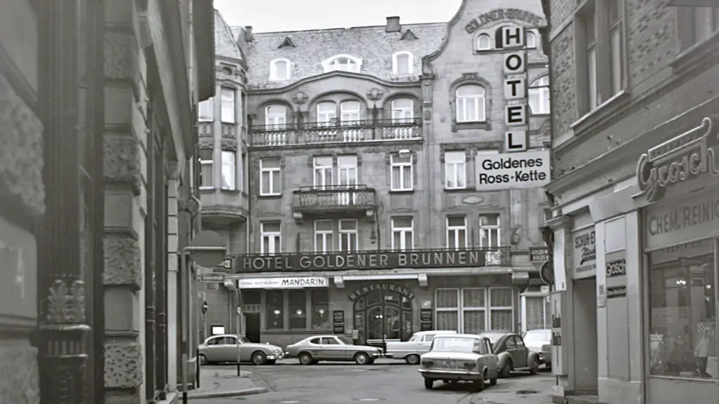 Schwarzweißaufnahme einer historischen Straßenszene in Wiesbaden mit klassischen Gebäuden und Autos.